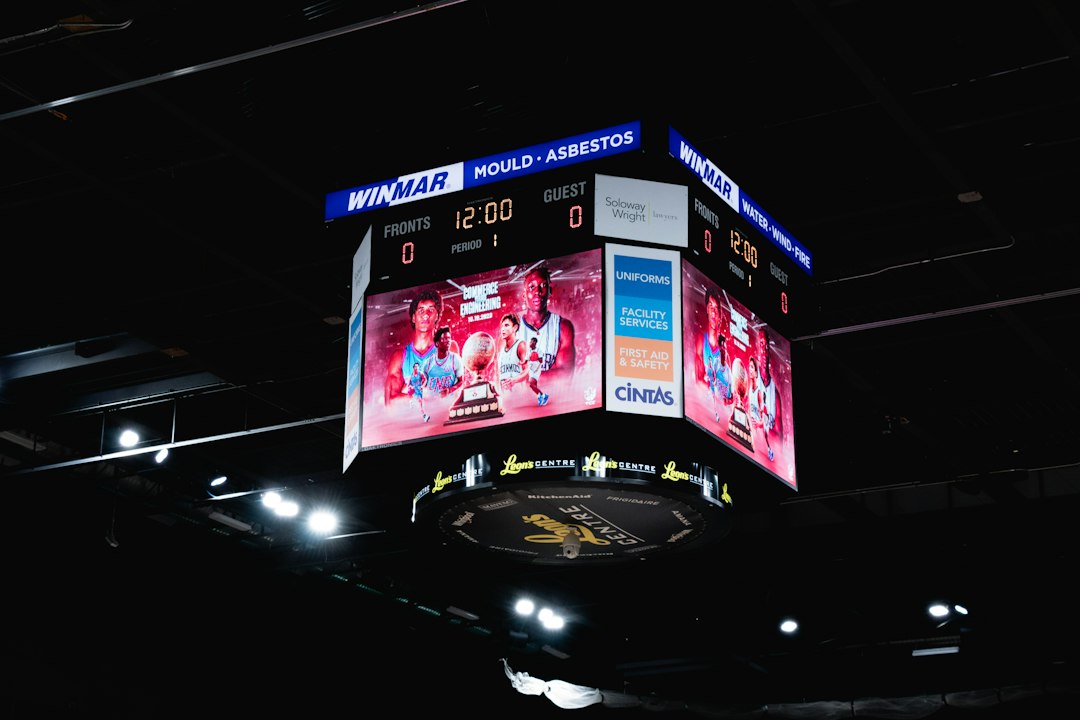 An arena scoreboard lit up above a darkened arena, showing 12:00 on the game clock