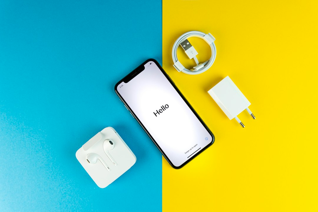 A new iPhone on its Hello setup screen, the step where an eSIM is transferred or activated, beside its cable and charger