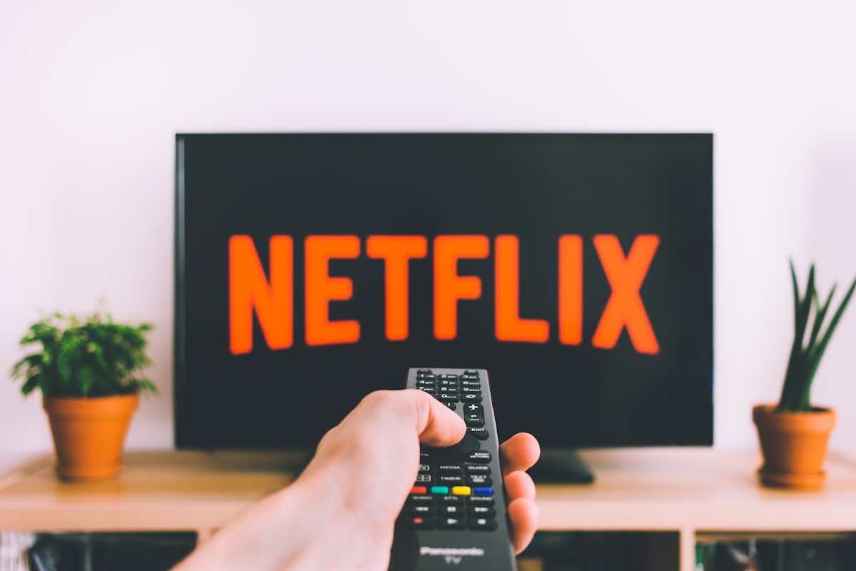A hand pointing a remote at a living room TV showing Netflix, the setup where error M7111-5059 or E106 appears
