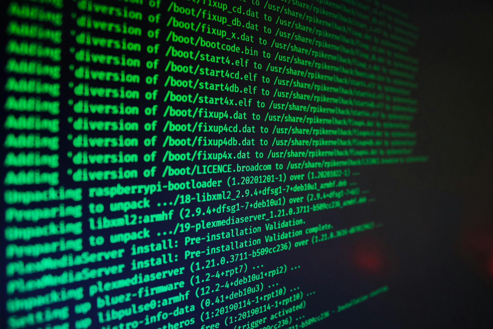 Dark terminal screen filled with green package-install log lines, photographed at an angle